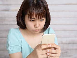 スマホでイライラする女性の画像